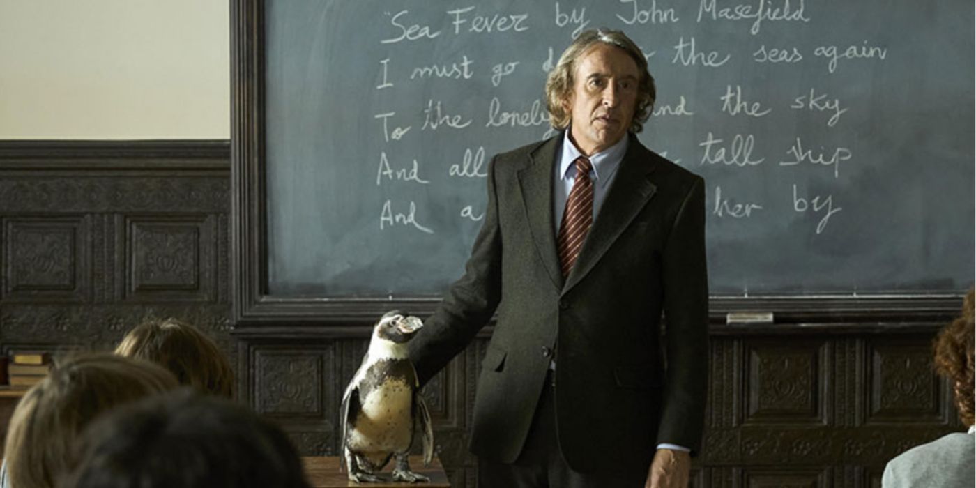 Steve Coogan standing in front of a classroom with a penguin at his side in 'The Penguin Lessons'.