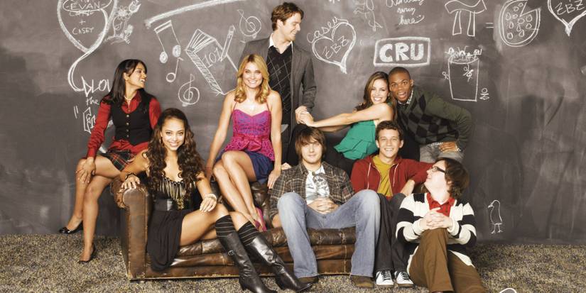The nine-person ensemble cast of the series 'Greek' posing and smiling, some to each other, while others are looking into the camera