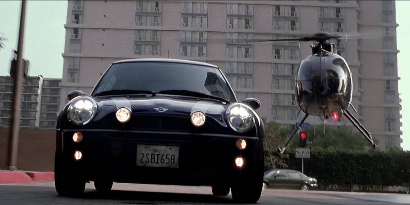 A blue Mini Cooper outraces a low flying helicopter in 'The Italian Job'