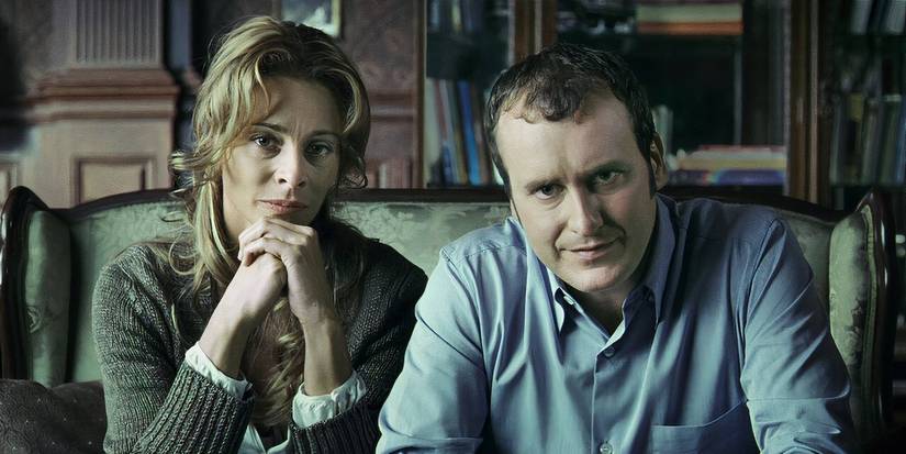 Belen Rueda and Fernando Cayo as Laura and Carlos sitting next to each other on a loveseat in "The Orphanage" (2007)