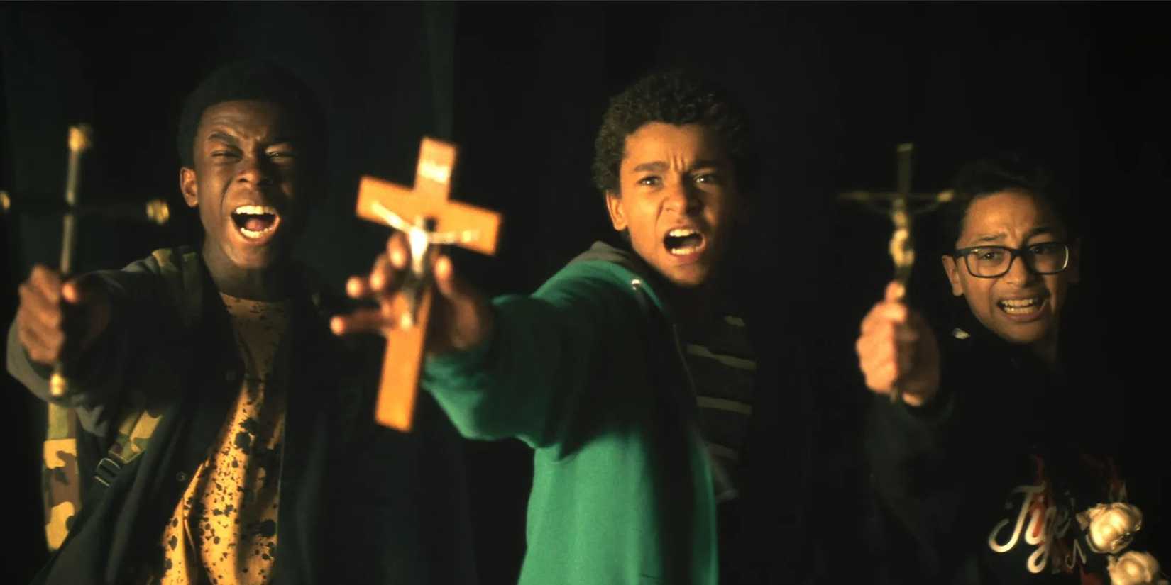 Three teenagers hold up crosses and look afraid in Vampires vs. the Bronx
