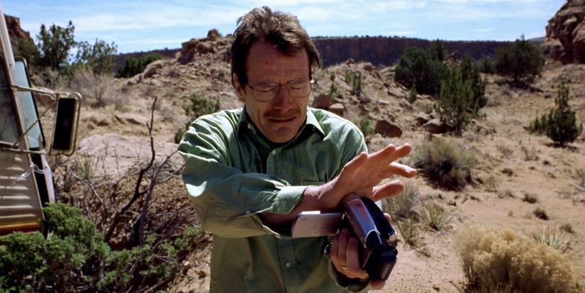 Walter holds a video camera and looks desperate, standing in a desert in the Breaking Bad pilot episode.
