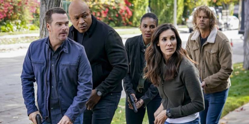The cast of NCIS: Los Angeles Season 14 creep along a sidewalk with weapons drawn.