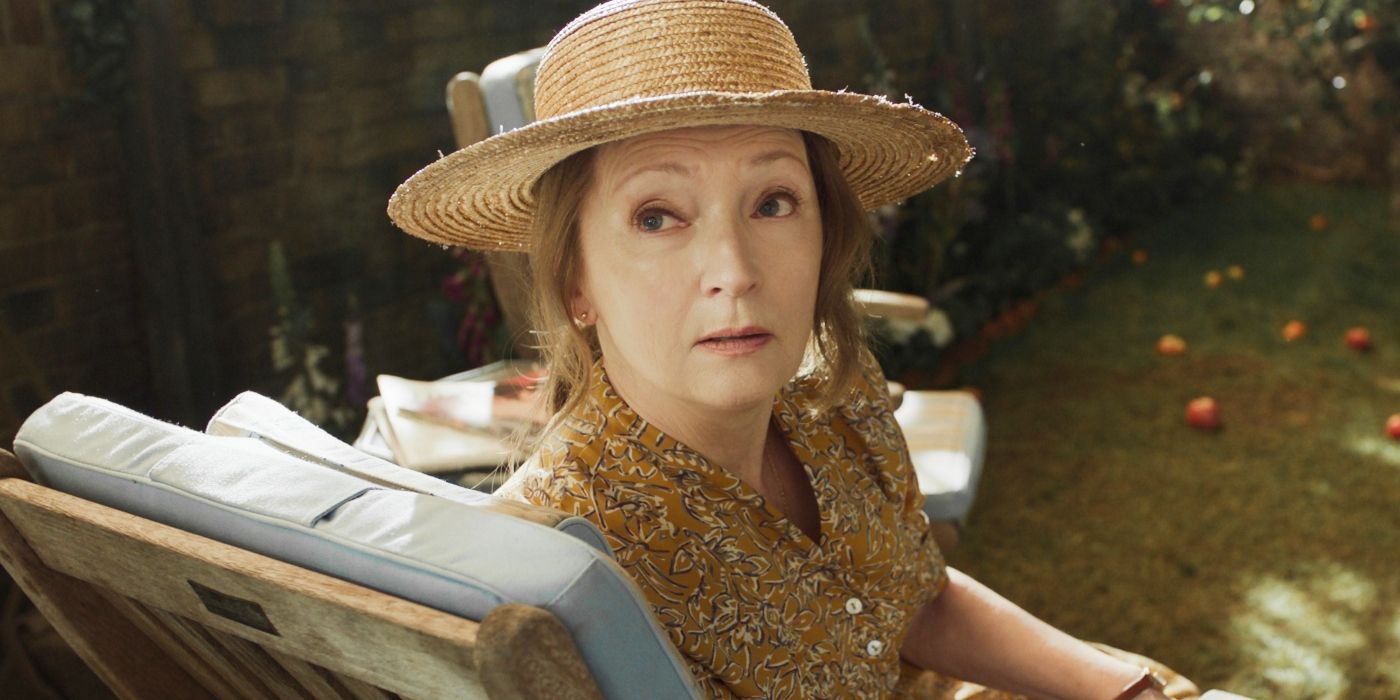 Nancy de Lesley Manville sentada afuera escuchando a alguien (Descargo de responsabilidad)