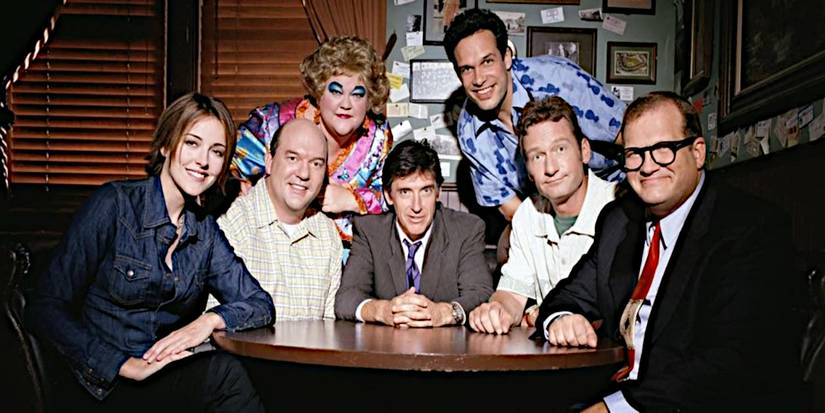 The cast of the Drew Carey Show poses for a promotional photo in a bar.