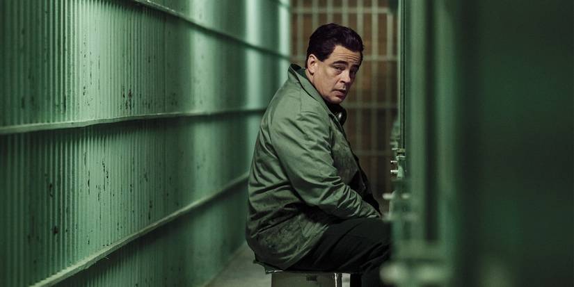 Benicio del Toro sitting on a bench with barred walls around in 'Escape at Dannemora.'