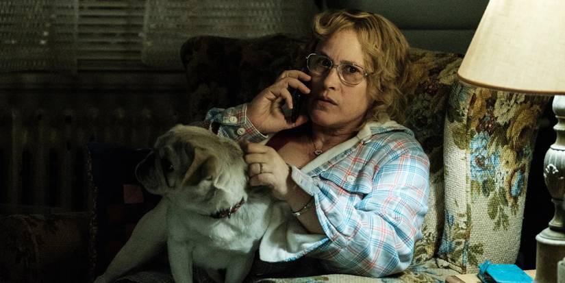 Patricia Arquette sits in a chair talking on the phone with a dog on her lap in Escape at Dannemora.