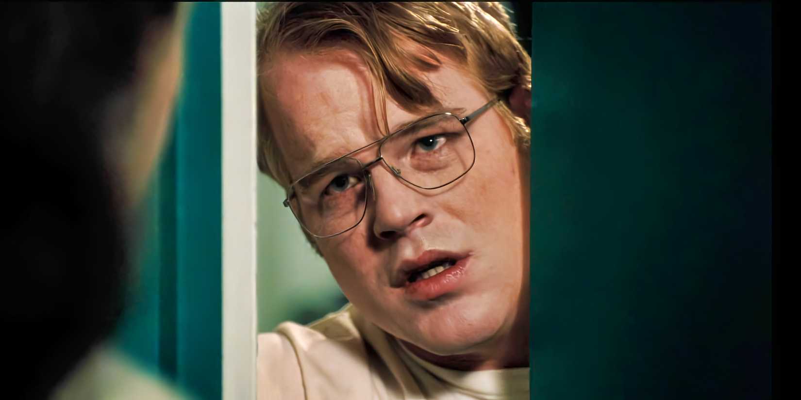 Philip Seymour Hoffman peers through a cracked door and has a worried look on his face in Happiness.