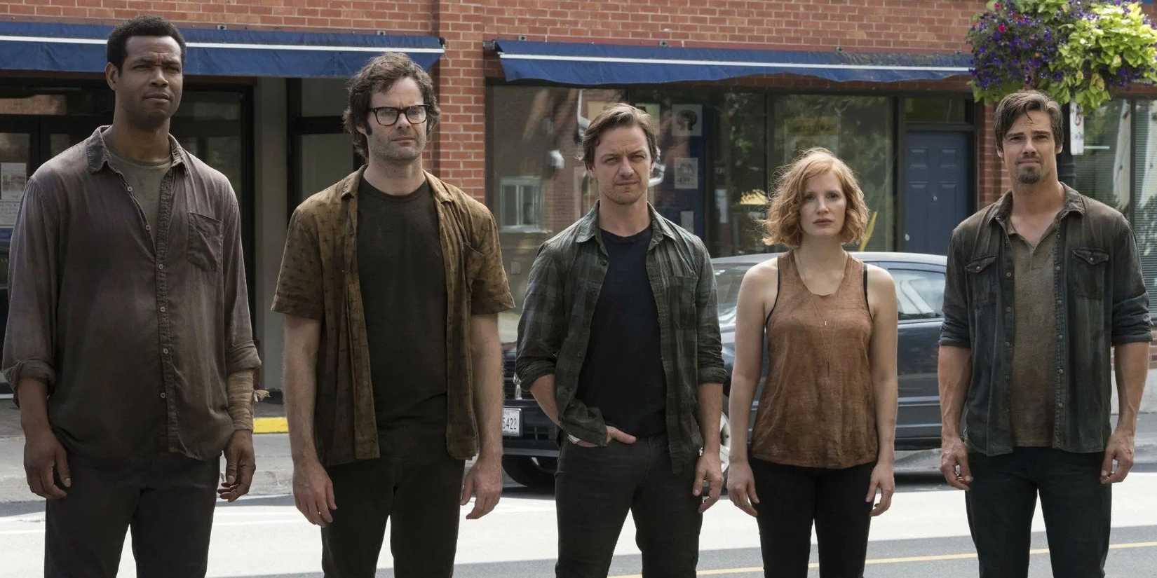 The adult versions of Mike, Richie, Bill, Beverly, and Ben stand on a street in It Chapter Two.