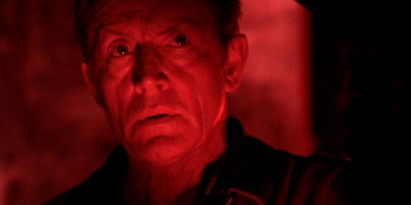 Frank Black (Lance Henriksen) covered in red light on a film set in 'Millennium'