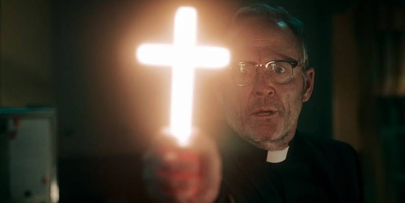 John Benjamin Hickey as Father Callahan wields a glowing cross in 'Salem's Lot' (2024).