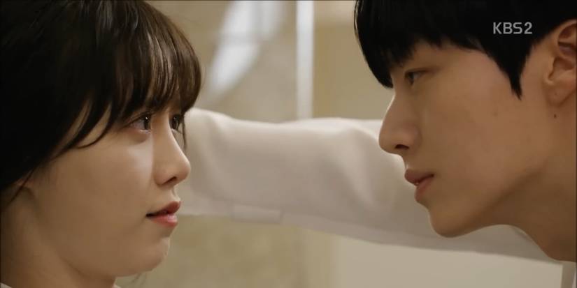 Park Jisang has Yoo Ri-Ta blocked against a wall as they have an important conversation, both of them longingly staring into each other's eyes, in the K-Drama "Blood."