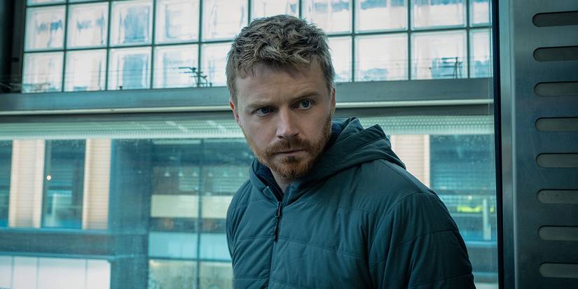 Jack Lowden standing in front of a window in Slow Horses Season 4.