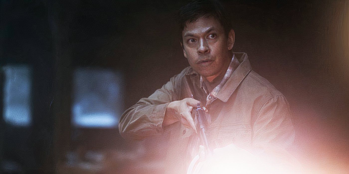 Chaske Spencer as Ruben holding up a rifle and flashlight outside in the dark