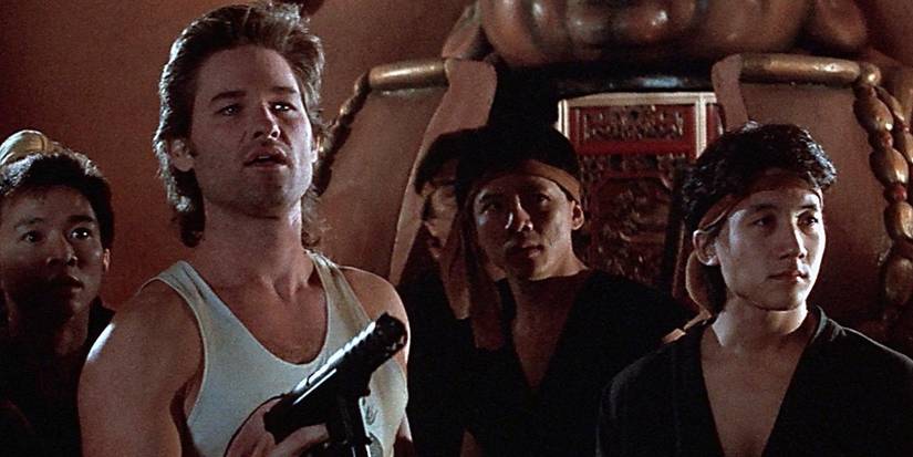 Kurt Russell as Jack Burton holding a weapon with people nearby in 'Big Trouble in Little China'.