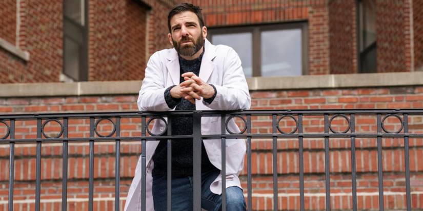 Zachary Quinto as Dr. Oliver Wolf leaning on a railing outside of the hospital in Brilliant Minds