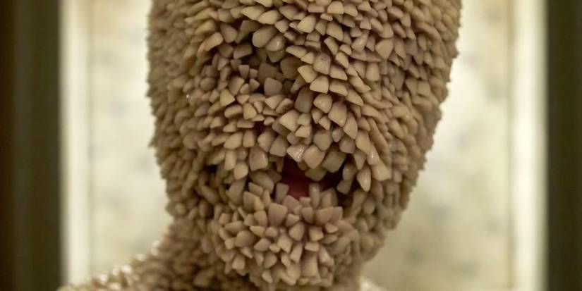 Eddie Painter aka the Tooth child, covered in teeth, from Channel Zero: Candle Cove looking at the screen.