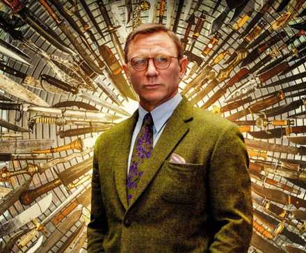 Daniel Craig as Benoit Blanc standing in front of a wall full of knives in Knives-Out.