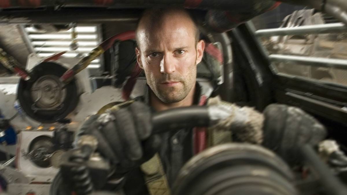 Jason Statham looks focused, sitting in a rugged vehicle in Death Race.