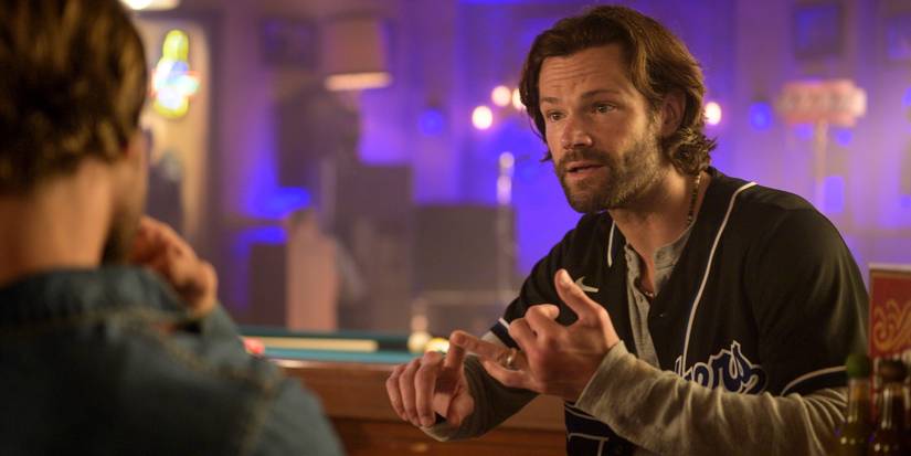Jared Padalecki as Camden Casey sitting in Smokey's wearing a Dodgers jersey on Fire Country.