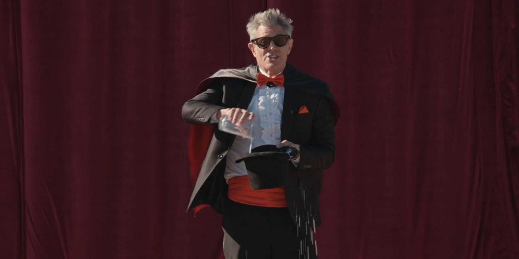 Johnny Knoxville pours a glass of milk into a magician's hat in 'Jackass Forever'.