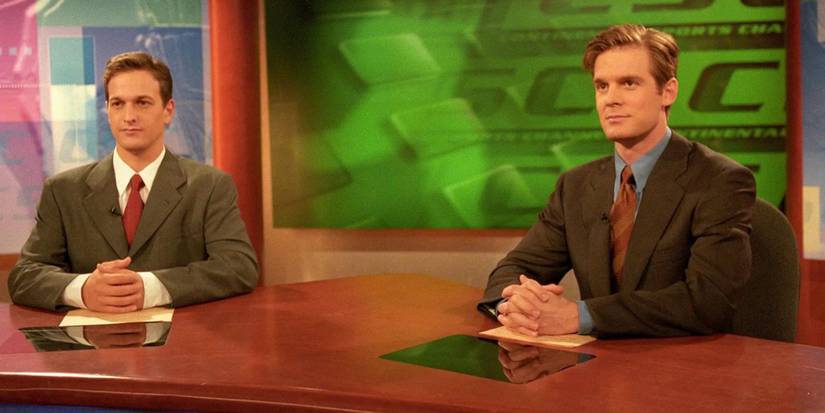 Josh Charles and Peter Krause wear suits as they sit at the anchor news desk