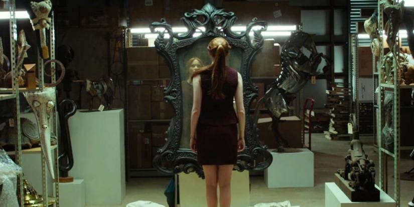 Karen Gillan berdiri di depan cermin besar dengan bingkai hitam berornamen di 'Oculus'