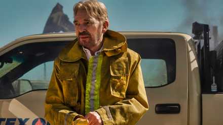 Billy Bob Thornton parado frente a un camión con una chaqueta de trabajo Landman.