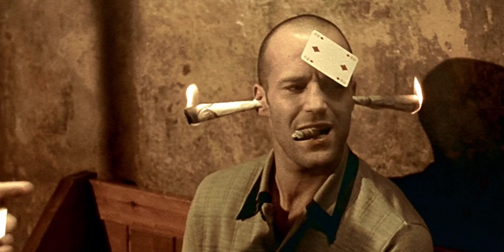 Jason Statham with two flaming papers on his ears and a card on his forehead in Lock, Stock, and Two Smoking Barrels.