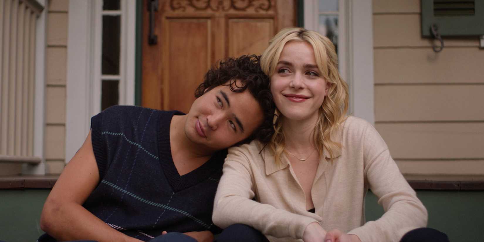 Kiernan Shipka as Jamie and Nico Hiraga as Ben sit on porch steps and smile in Sweethearts.