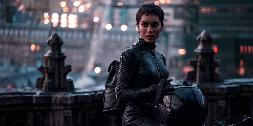 Zoe Kravtiz as Selina Kyle on a motorcycle holding a helmet on a bridge in The Batman.