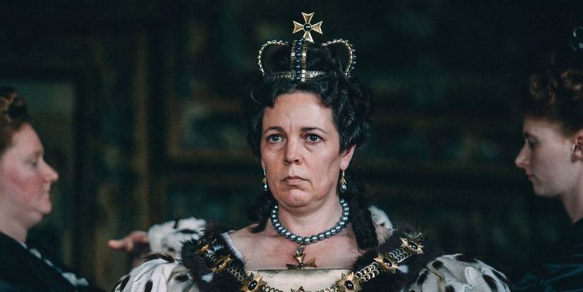 Olivia Colman mengenakan mahkota kerajaan dan gaun megah serta tampil serius di The Favorite. 