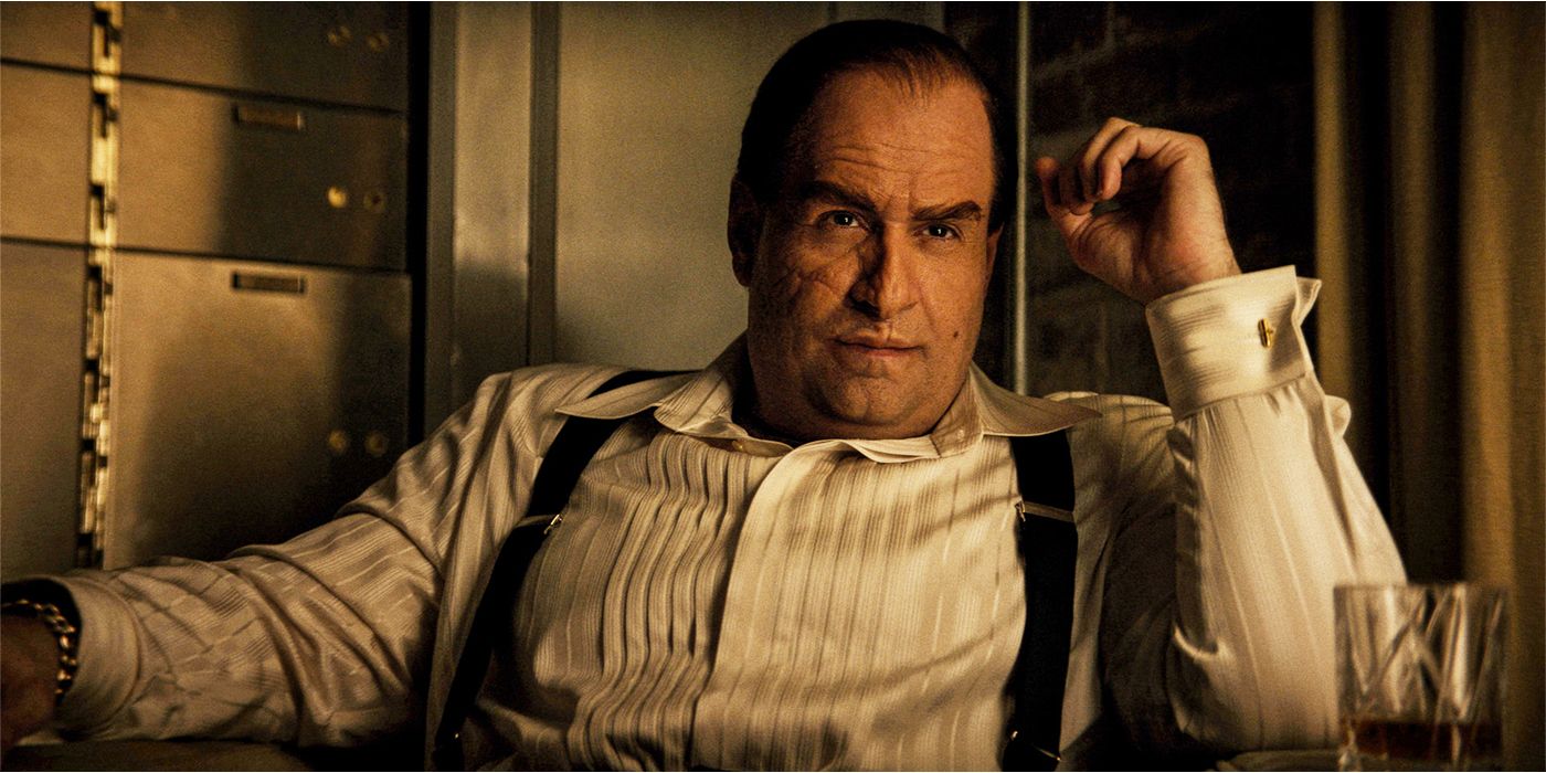 Oz (Colin Farrell) seated in a dress shirt and suspenders looking up skeptically in The Penguin.