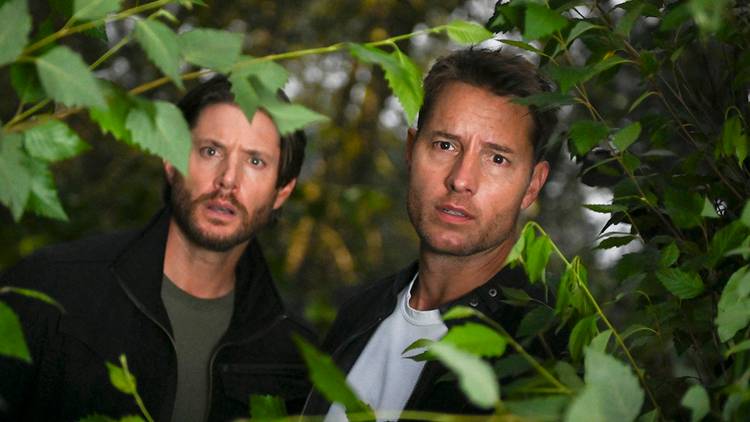 Justin Hartley as Colter Shaw and Jensen Ackles as Russell Shaw in Tracker peaking through trees