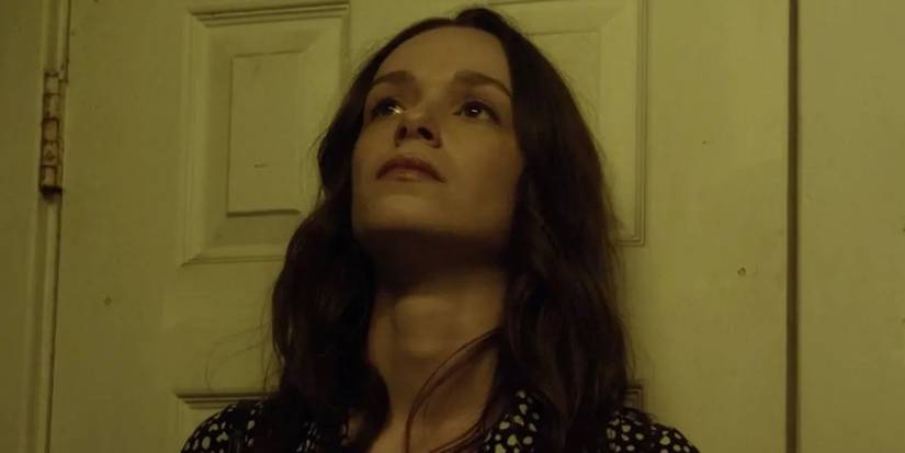 Sarah, played by actor Alexandra Essoe, leaning against a door in Starry Eyes