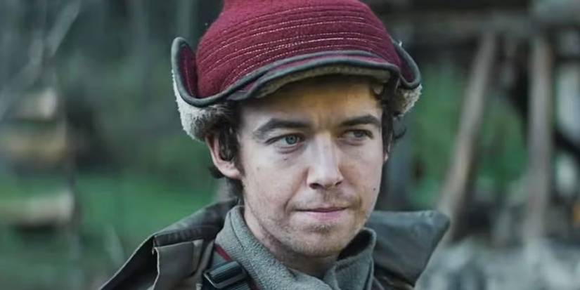 Alex Lawther as Karis Nemik wearing a hat and coat and standing outside looking off camera in 'Andor.'