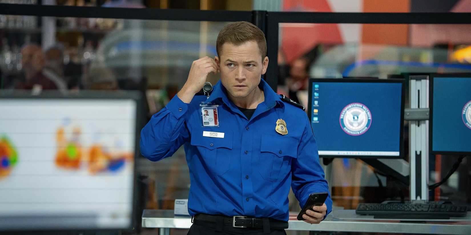 Taron Egerton as Ethan Kopek putting on an ear-piece in Carry-On