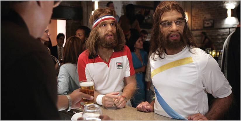 Two cavemen in tennis apparel sit at a bar in Cavemen