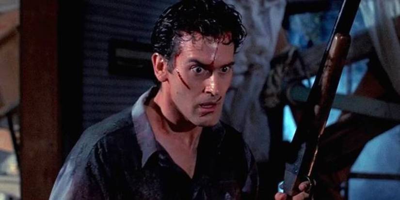A bloodied and sweaty Ash Williams (Bruce Campbell) holds up a shotgun as he searches, wide-eyed, around a cabin in 'The Evil Dead' (1981).