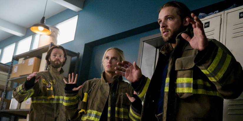 Jared Padalecki, Leven Rambin, and Max Thieriot as Camden, Audrey, and Bode, respectively, all holding their hands up while in firefighter gear on 'Fire Country.'