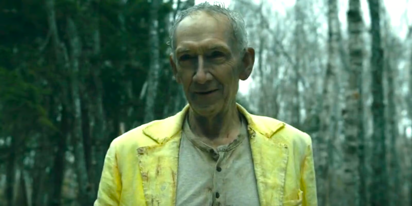 The man in yellow standing in the woods in From