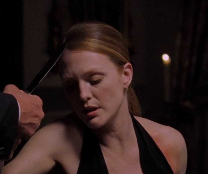 Julianne Moore as Starling sits at a fancy dinner table in Hannibal (2001)