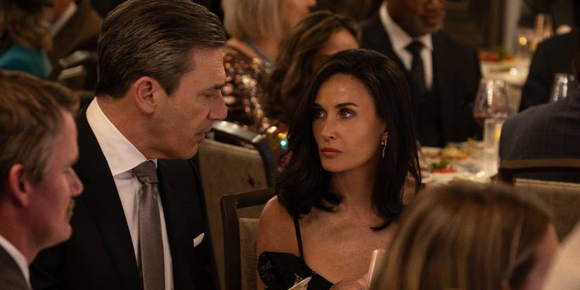 Jon Hamm and Demi Moore sitting at a table during a dinner function in Landman.