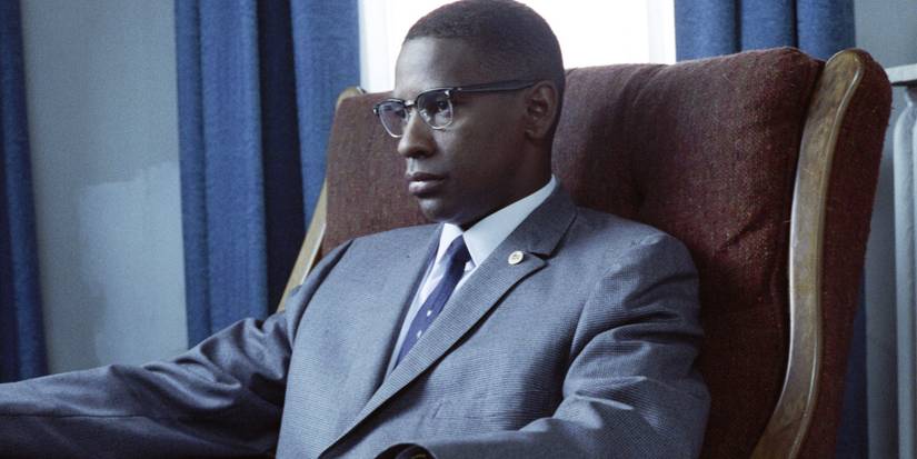 Malcolm (Denzel Washington) sitting in a chair in Malcolm X.