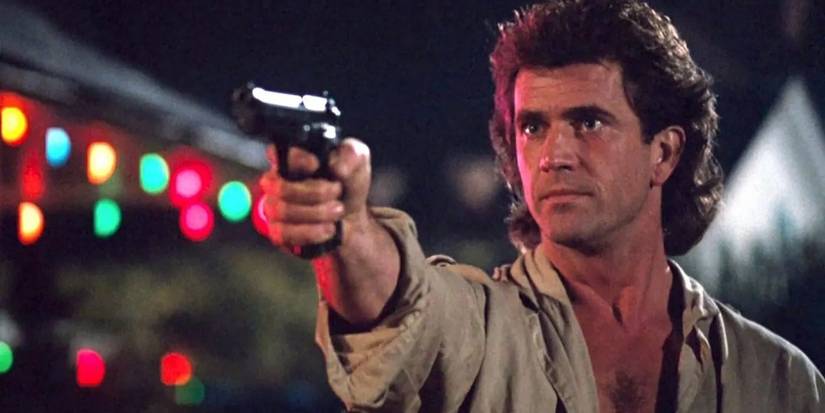 Mel Gibson as 'Riggs' pointing a gun while Christmas lines sparkle in the background in Lethal Weapon