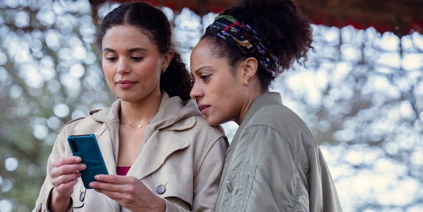 Rosalind Eleazar and Jessica Plummer looking at a cell phone in Missing You.