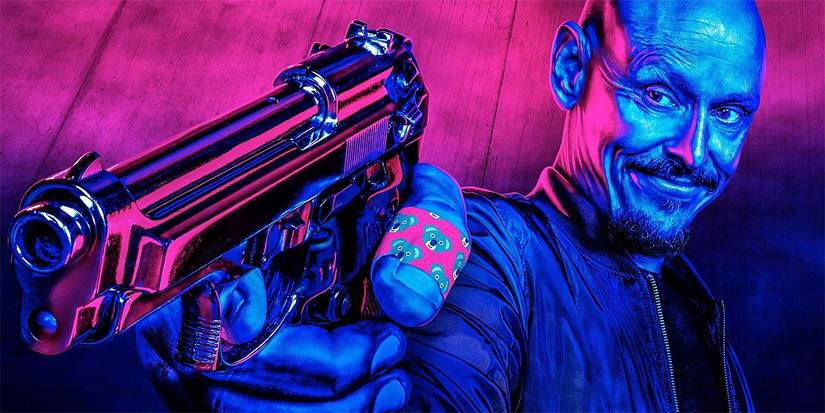 Scott Ryan in blue and pink lighting while holding a gun at the screen in Mr. Inbetween