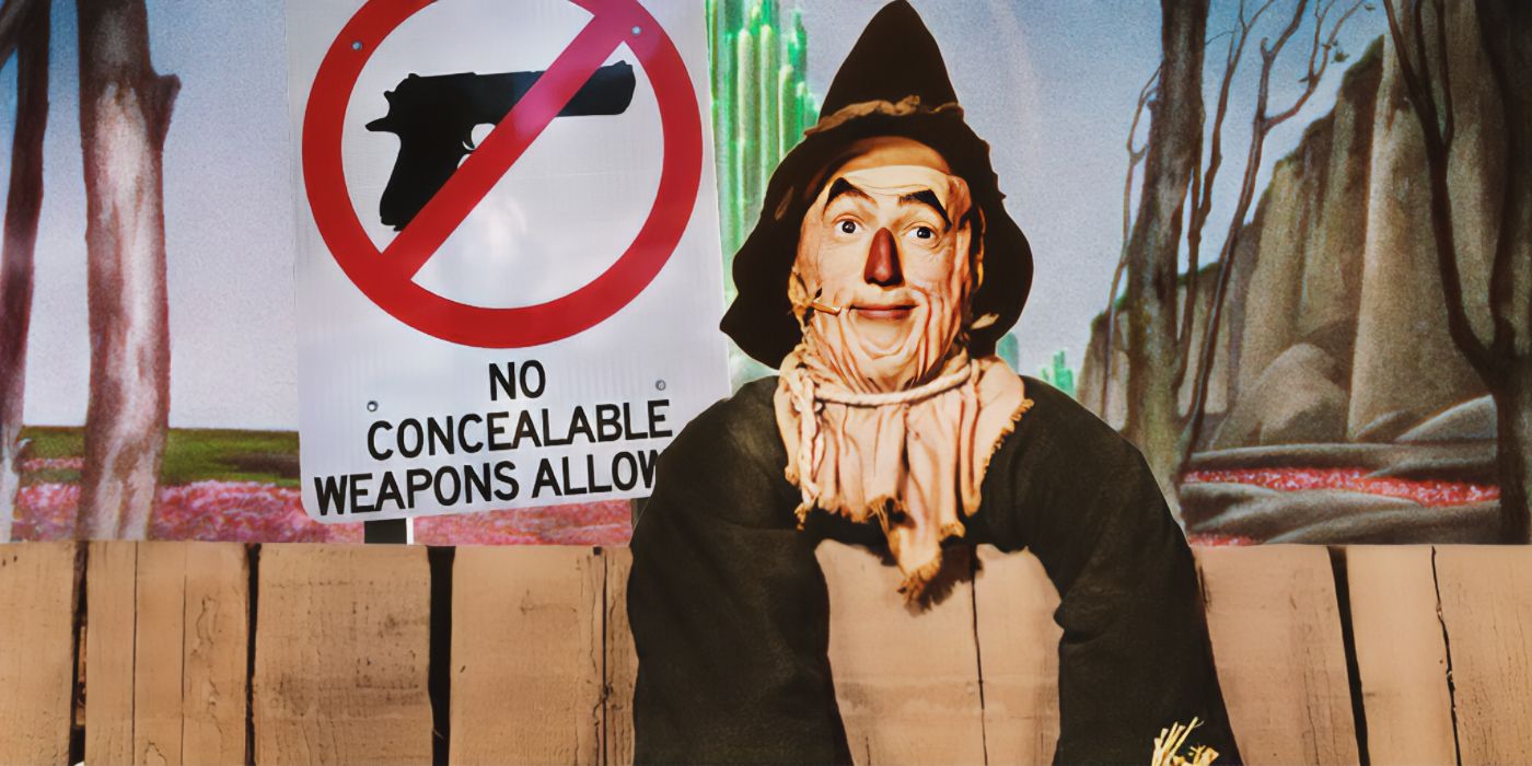 Scarecrow, played by actor Ray Bolger, leaning over a fence with the Emerald City and a sign prohibiting firearms in the background.