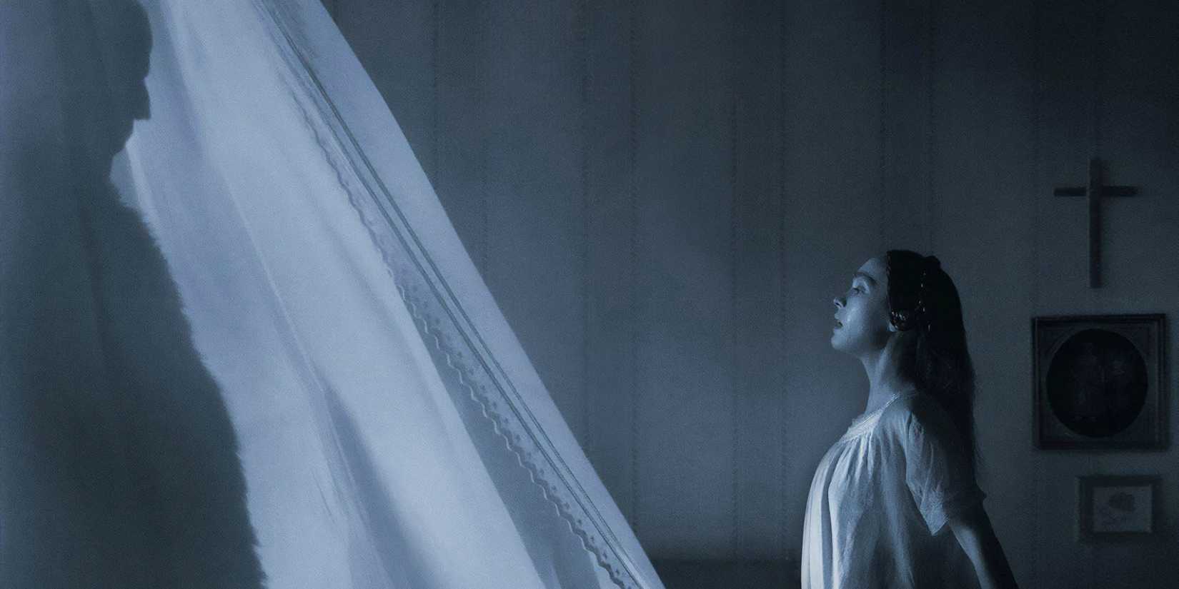 Count Orlok in the shadows of a curtain stands in front of Ellen Hutter in 'Nosferatu'