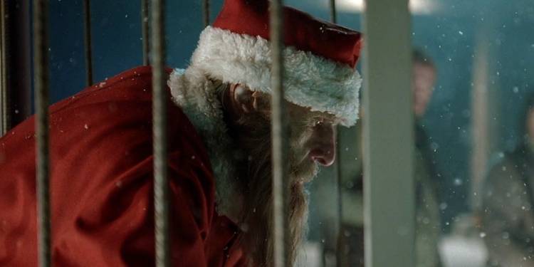 A thin, dirty old man dressed as Santa sitting inside a cage outside in the snow in "Rare Exports"